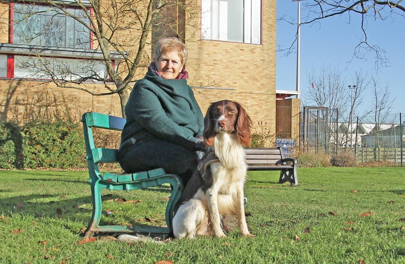 District Councillor Bunty Waters with George, her friendly and well-behaved spaniel, in the green space in front of Bar Hill church. “I always want to do the best for Bar Hill residents,” she says.